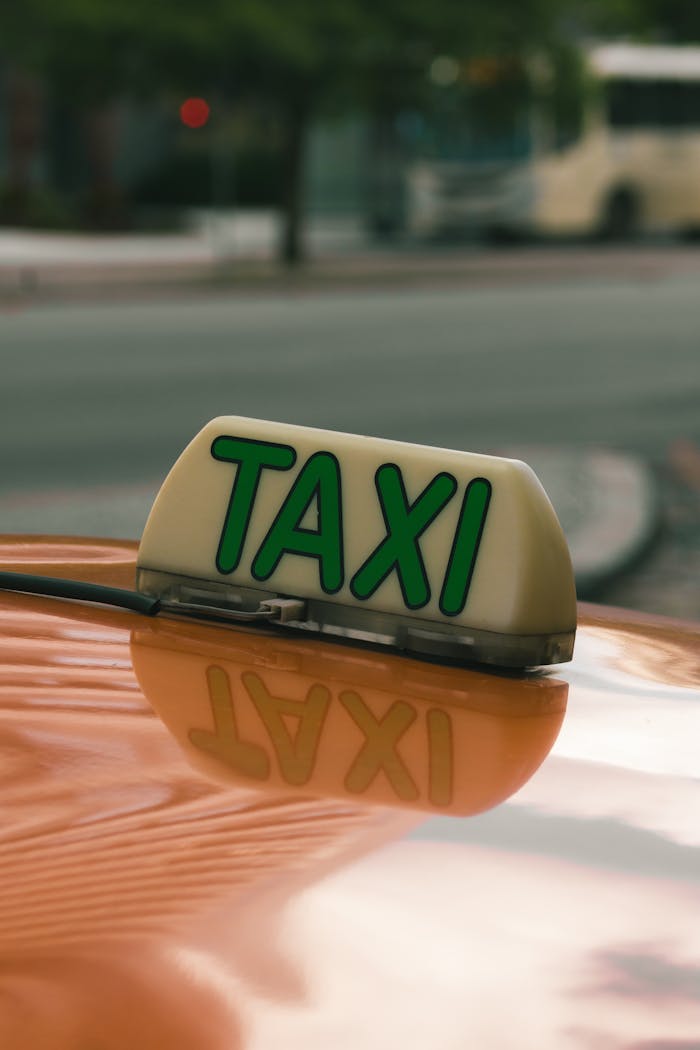 A close-up image of an orange taxi with a 'TAXI' sign on a city street, showcasing urban transportation.